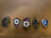 Five distinct Soviet military badges laid out on a wooden surface, showing front designs including stars and shields