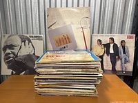 Photo of a stack of mixed vinyl records showing covers including Bill Ward's Great Organ Polkas & Waltzes, The Crusaders, Paul Robeson, and Huey Lewis & The News.