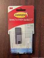 Front view of unopened 3M Command Smartphone Caddy packaging showing brand, product, damage-free hanging feature, and clear plastic caddy holding slots.