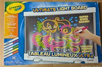 Front view of the Crayola Ultimate Light Board packaging showing the board with colorful octopus drawing and 6 neon markers below it.