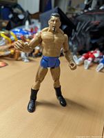 Front view of the articulated Dave Bautista action figure standing on a table, showing detailed muscular build and black boots with blue trunks.