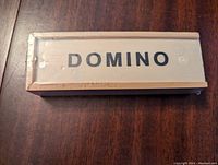 Top view of unopened wooden domino box showing the word 'DOMINO' on the lid.