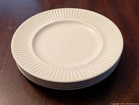 Stack of four white ceramic Athena side plates showing raised ribbed pattern on the rims.