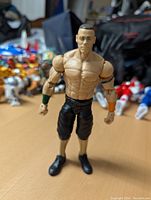John Cena wrestling action figure standing upright showing front view with detailed musculature and colored wristbands.