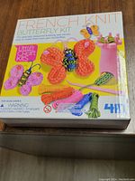 Front of the box showing 4M French Knit Butterfly Kit. Box depicts colorful yarn butterflies, knitting tool, and yarn strands preparing for crafting.