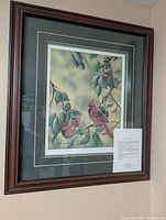 Framed print of cardinals on tree branches with green double mat and wooden frame.