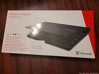 Box front showing Microsoft Universal Mobile Keyboard with logo, product image and compatibility info including Windows, iOS, and Android.