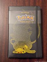 Front cover of the Moleskine Pokemon journal showing gold dotted Pikachu artwork and Pokemon logo band.