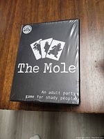 Front of The Mole card game box showing the game title, tagline, and artwork. The box is sealed in plastic.