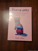 Front of the sealed Thera-pets box showing colorful illustrated cat and author name.