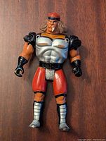 Front view of the 1986 LJN Thundercats Grune the Destroyer figure showing orange skin, silver chest armor, red pants, black gloves and boots, and red headband.