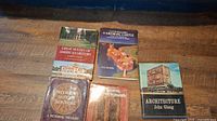 Five hardcover books arranged on a wooden surface showing covers and titles relating to architecture, history, and ironwork art.