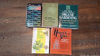 Five books laid out on a wooden surface, titles visible including Animal Health, Organic Gardening, House Plants, and Honey & Spice.