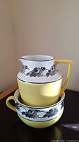 Image showing stacked yellow ceramic chamber pot and pitcher with gray floral designs on white band near top.