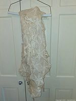 Front view of cream crocheted bed cover hanging on hanger