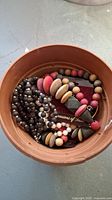 Top view of multiple beaded necklaces and bracelets placed in a brown container, showing variety in bead colors and styles.