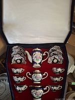 Tea set in box, showing teapot, sugar bowl, creamer, and set of teacups and saucers arranged inside velvet-lined presentation box.