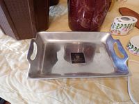 Silver metal tray with handles and label visible