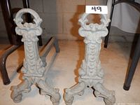 Photo of the pair of cast iron log holders showing their ornate design, textured surface, and three curved feet on each holder.