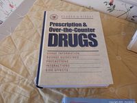 Closed 'Reader's Digest Prescription & Over-the-Counter Drugs' book on a yellow tablecloth
