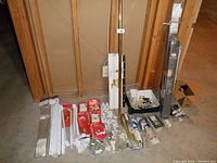 Full view of the assortment of home repair parts including drawer slides, Closetmaid brackets, fan blades, door closer, extension pole, plastic casters, curtain hooks, blind brackets, garage door parts, and shower rod and hooks.