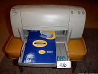 Photo of the HP Deskjet 930C printer with front paper tray open showing the manual inside the tray.