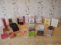 Lot of 24 assorted inspirational and religious books displayed on table with floral wallpaper background. Includes a variety of sizes and covers, mostly soft and hardcover books.
