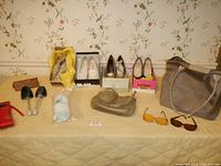 Full lot overview showing shoes, handbag, sunglasses, umbrella, shoe forms, and travel bag on bed against floral wallpaper.