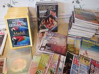 Photo showing stacks of National Geographic, Food & Wine, Southern Living, Home and other magazines arranged on a surface in an indoor setting with wallpaper background