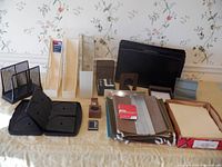 Various office storage supplies spread on a table including folders, briefcase, metal and plastic organizers, and desk accessories.