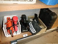 Photo showing assortment of tools including Black & Decker jigsaw, orange/red soldering iron and hair dryer, Craftsman oscillating belt sander with dust bag, and black Coleman carrying case.