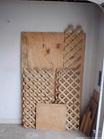 Five wood dollies stacked with lattice panels and a solid plywood board leaning against a wall in a garage setting
