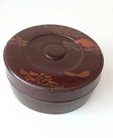 Top view of round lacquer box with hand painted floral and bird motifs on lid.