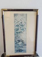 Full view of framed Chinese vintage print depicting mandarin ducks, foliage, calligraphy and several seals in a gold and dark wood frame.