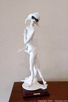 Full view of white porcelain Lady Harlequin figurine with black mask, posed on one leg with detailed costume and base.