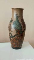 Front view of stoneware vase showing detailed peacock artwork.