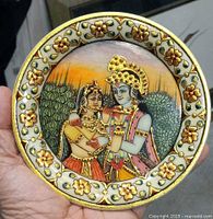 Close-up of the circular marble plate showing Radha Krishna painting and detailed floral border with gold accents.