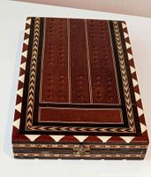 Top view of the folding wooden box showing geometric inlays and drilled hole decorations on dark wood surface with mosaic border.