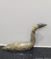 Side profile of the green stone loon sculpture against a plain background