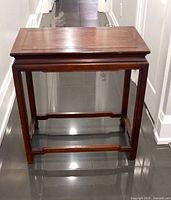 Front view of the rectangular wooden table showing the legs and apron structure in Ming design style on a glossy floor.