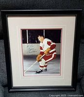 Framed signed photo of Gordie Howe in Red Wings gear on the ice, photo shows the full front of the black decorative frame.