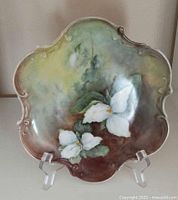 Front view of porcelain wall plate with hand painted Ontario Trillium flowers and soft earthy background colors