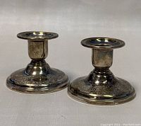 Front view of pair of vintage Birks sterling silver weighted candle holders showing round wide bases with intricate engraved designs.