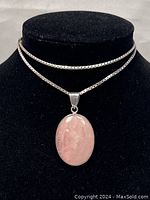 Full view of the necklace on a black display stand showing the silver chain and rose quartz pendant.