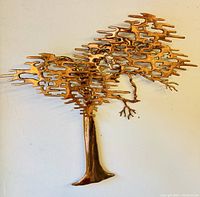 Front view of brass tree wall sculpture showing stylized canopy and trunk.