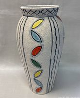 Front and side views of the hand-painted ceramic vase featuring colorful leaf motifs on a textured white background.