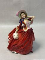 Front and side views showing the figurine's detailed red dress, bonnet, and purse