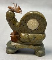 Front view of the Inuit soapstone hunter carving showing the carved face detail and feathers attached to the head.