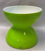 Green hourglass-shaped ceramic vase with white inside, showing base signature by Anne Nilsson.