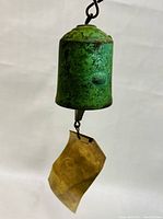 Photo of green patina bronze wind bell with brass wind catcher showing embossed shell motif.